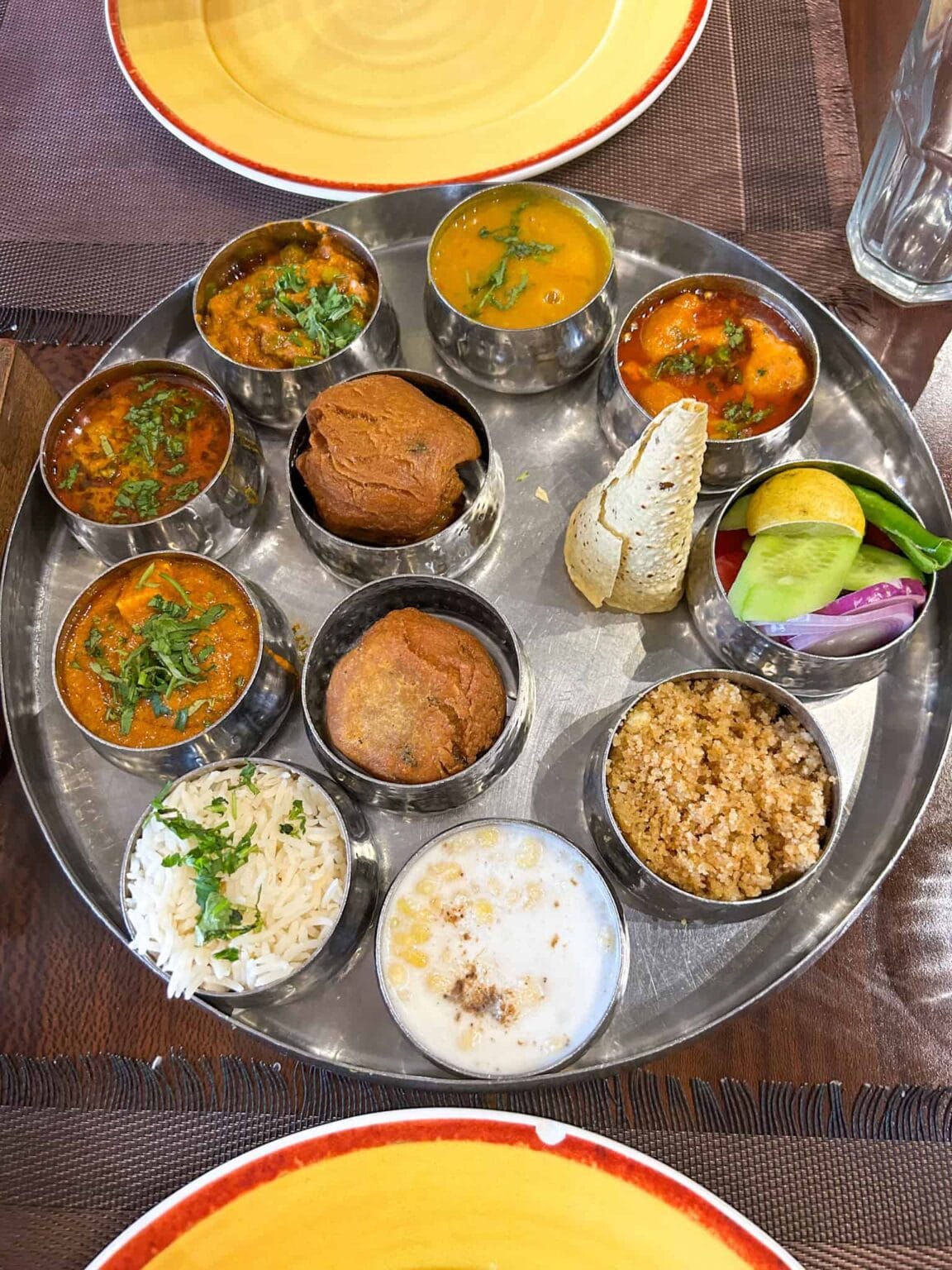 Close-up of an elaborate Rajasthani thali in Jaipur, Rajasthan, India with a variety of regional dishes like dal baati churma, gatte ki sabzi, rice, papad, served in steel bowls